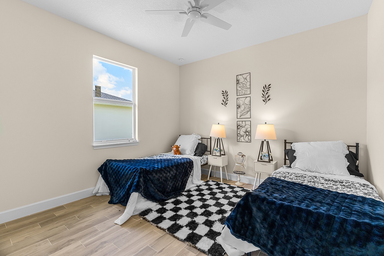 Staged secondary bedroom with two beds in an Osuna Homes model